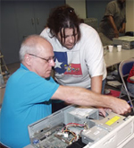 Instructor working with a student taking a computer apart
